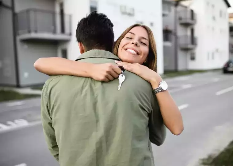 Pareja abrazados y sosteniendo llave de hogar