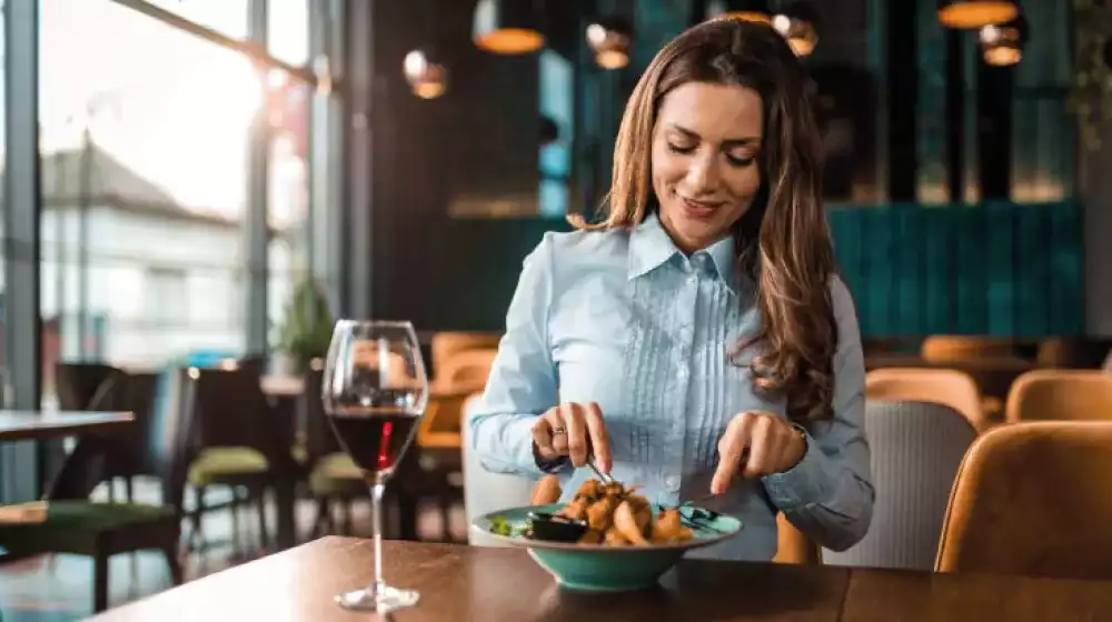 Mujer comiendo en restaurante, gracias a promociones BAC