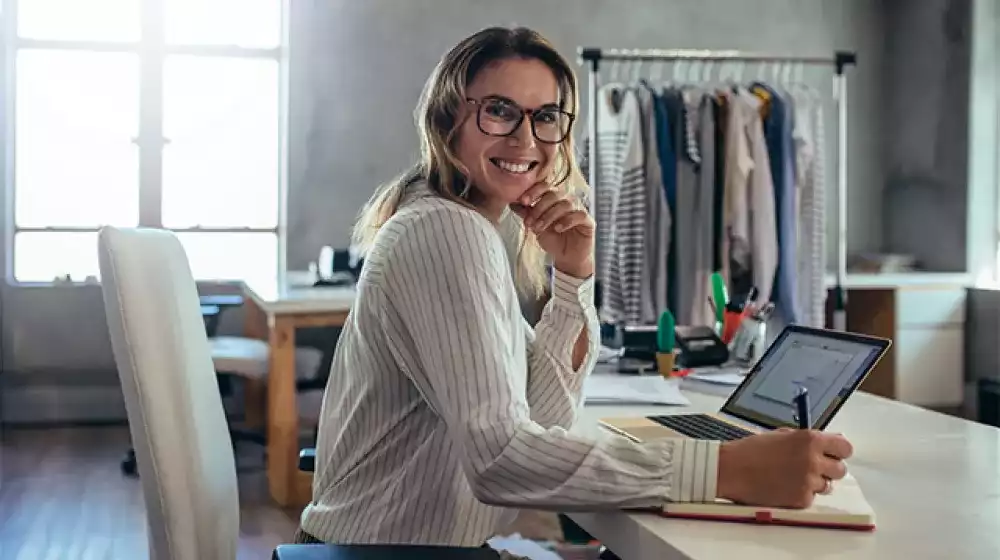 Mujer joven sonriente tomando nota de los pedidos de sus clientes.